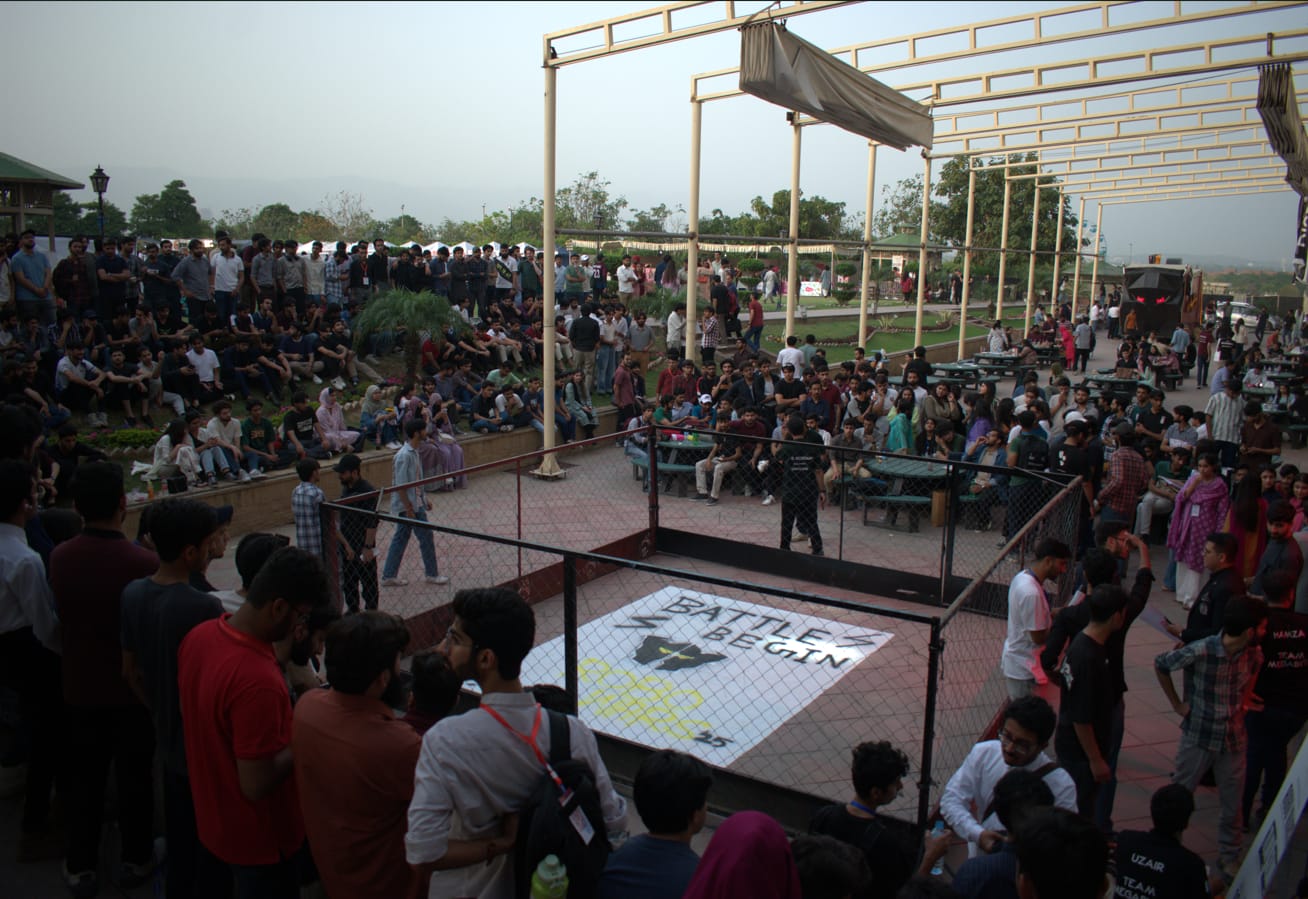 Spectators around a robotics battle arena